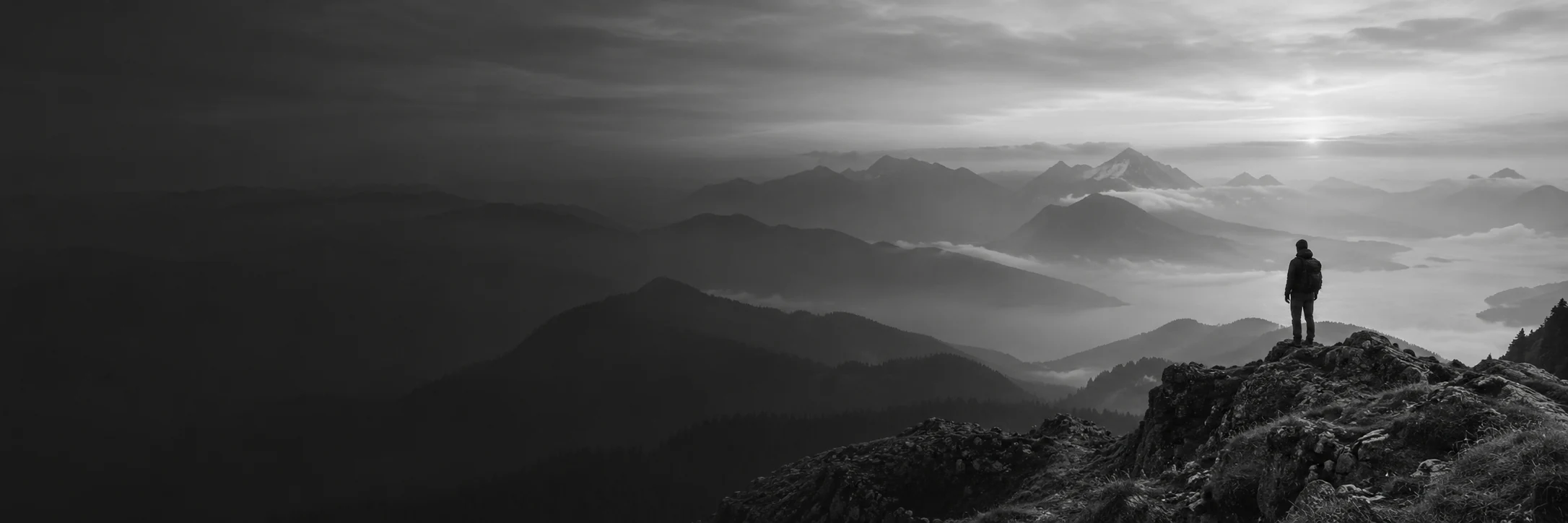 Une personne face à un paysage de montagnes brumeuses